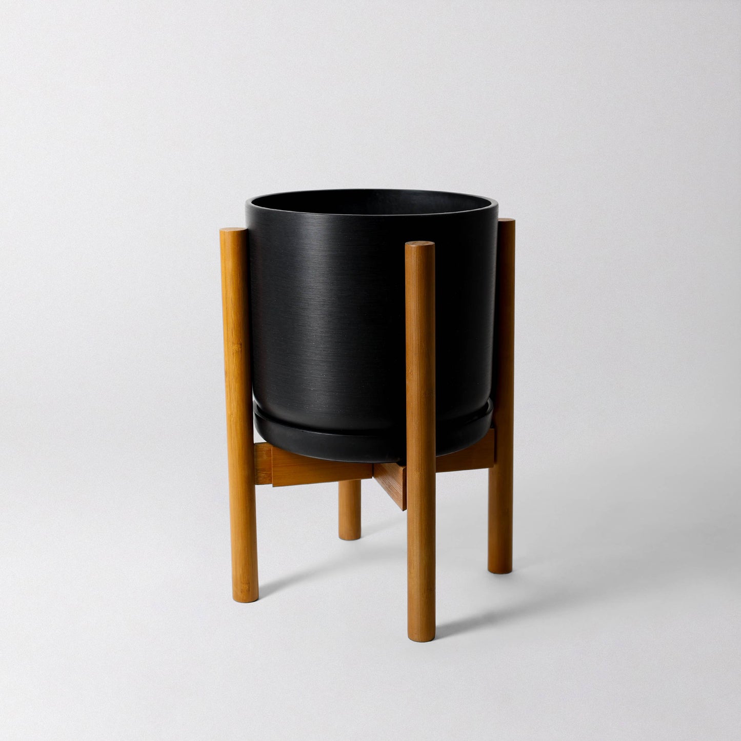 Stylish adjustable bamboo 'Aspen' plant stand from Luxe Leaf Decor, set to a shorter configuration, holding a black Luxe Leaf Decor planter.
