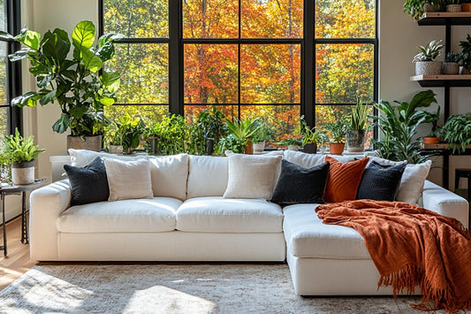 A modern living room featuring a large white sectional, surrounded by stylish indoor plants in sleek, contemporary planters and plant pots.